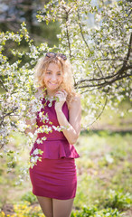 Fototapeta na wymiar Charming young girl in the spring cherry blossoms