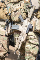 Soldiers in US Army Special Forces uniform, close up on rifle