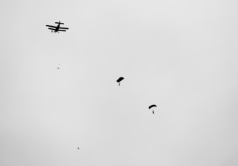 retro  biplane with skydivers in black and white