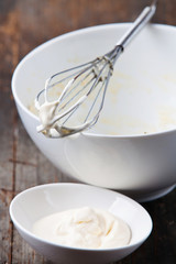 Homemade mayonnaise in bowl on wooden background