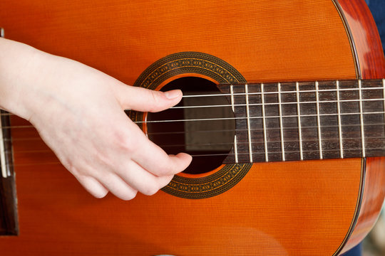 female hand plays on acoustic guitar