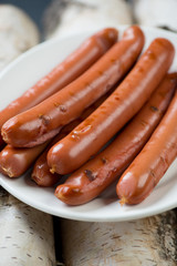 Close-up of a glass plate with grilled sausages on firewood