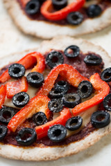 Vegetarian mini pizzas with olives and red bell pepper, close-up