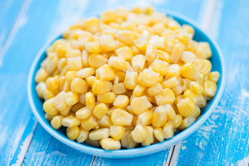 Plate with sweet corn kernels, blue wooden background