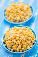 Sweet corn kernels over blue wooden background, vertical shot