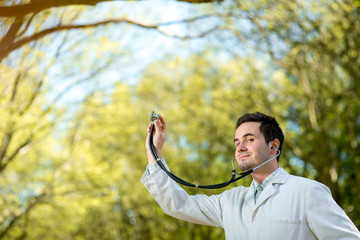 Young doctor listening with stethoscope