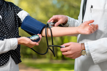 Young doctor measuring pressure to young lady