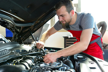 professional mechanic repairs engine of car - obrazy, fototapety, plakaty