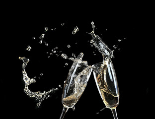 Glasses of champagne with splash, on black background