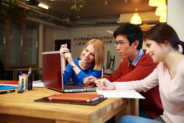 Happy students doing homework with laptop together