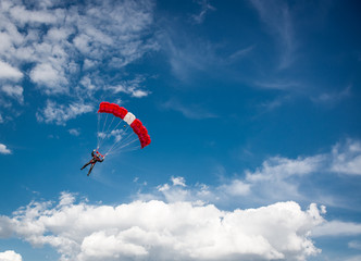 Parachutist over cloudy sky background