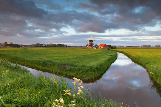 sunrise sky over windmill by river