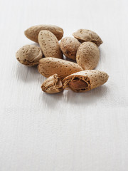 whole and broken almonds on white wooden table