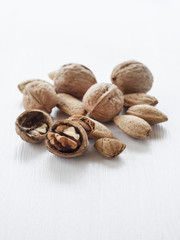 walnuts and almonds mixed on white wooden table.