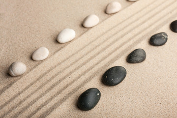 Fototapeta na wymiar Stripe of white and black stones lying on the sand