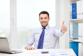 smiling businessman with laptop and documents