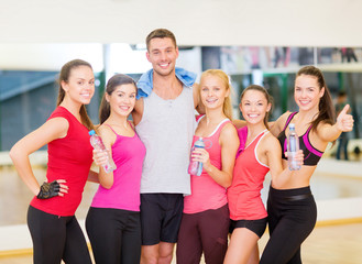 group of happy people in gym with water bottles