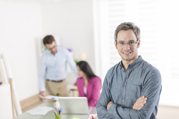 senior businessman standing in front of his colleagues in office