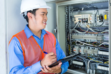 Asian Electrician at panel on construction site