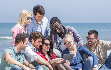 group of friends on the beach with tablet