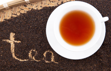 A cup of tea with the word TEA written on the dried tea leaves