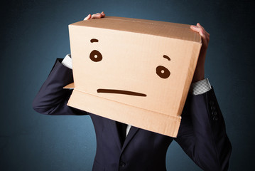 Businessman gesturing with a cardboard box on his head with stra