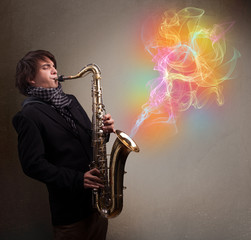 Obraz na płótnie Canvas Attractive musician playing on saxophone with colorful abstract