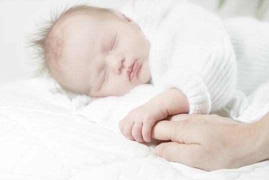 baby sleeping holding finger