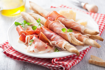 prosciutto ham and grissini bread sticks. italian antipasto