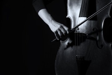 Beautiful woman holding a cello with selective light and black d