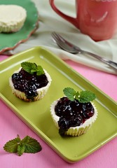 Mini-cheesecakes with berries and mint leaves