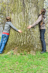 Boy and girl hugging old tree