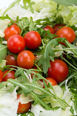 Heap of ruccola, lettuce leaves and cherry tomatoes