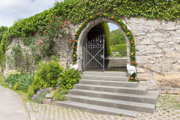 Mit Blumen geschmückter Friedhofseingang