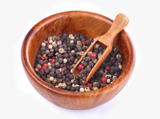 Peppercorns in bowl with a wooden spoon on a white