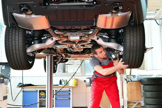 KFZ Mechaniker prüft Bremsen und Reifen am PKW