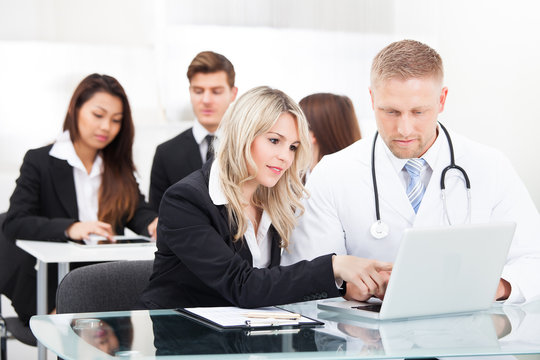 Male Doctor And Businesswoman With Laptop