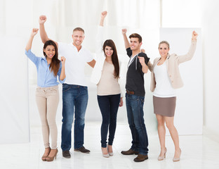 Confident Businesspeople Standing With Arms Raised