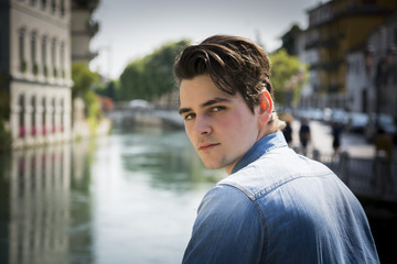 Young man wearing denim shirt on city bridge