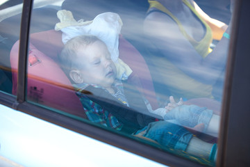 Toddler and his mom in back seat of car, boy is asleep