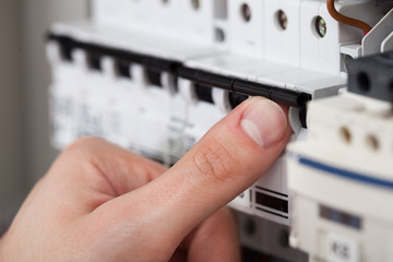 Technician Turning On Switch In Fusebox