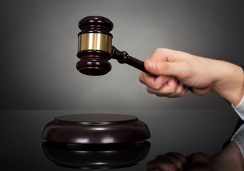 Male Judge Hitting Gravel At Desk