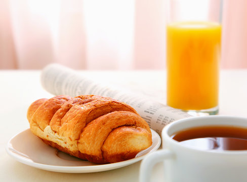Croissants, Coffee, Orange Juice and Newspapers on table