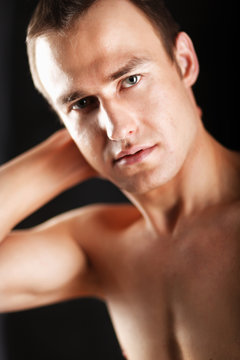Portrait of a naked muscular man, isolated on black background
