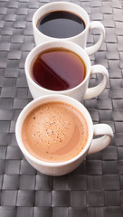 Hot beverages of chocolate, tea and black coffee on woven place 