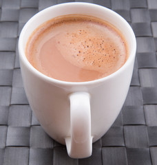 A mug of hot chocolate on a woven place mat.