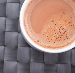 A mug of hot chocolate on a woven place mat.