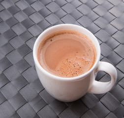 A mug of hot chocolate on a woven place mat.