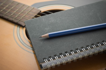 Notebook and pencil on guitar