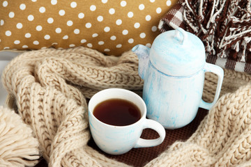 Cup and teapot with scarf on bed close up